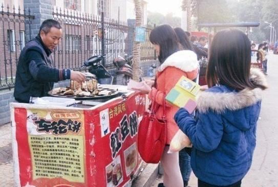 刘卫东(左)在湘潭大学开的这个卖红豆饼的小摊很受师生欢迎